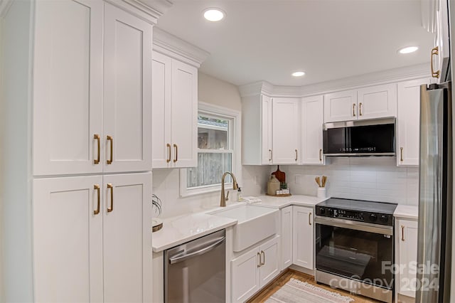 kitchen with sink, light wood-type flooring, tasteful backsplash, white cabinetry, and stainless steel appliances