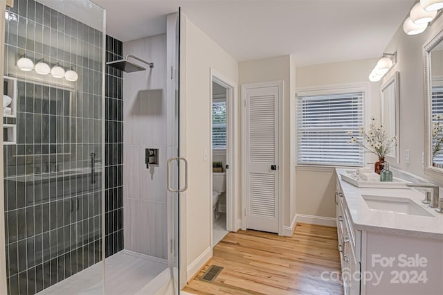 bathroom with hardwood / wood-style floors, vanity, an enclosed shower, and toilet