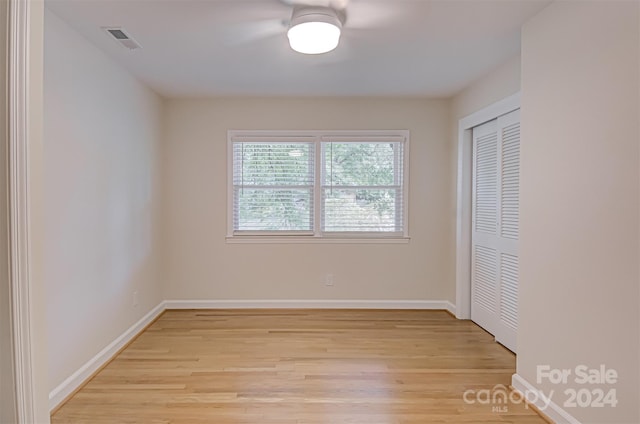 unfurnished bedroom featuring light hardwood / wood-style flooring, a closet, and ceiling fan