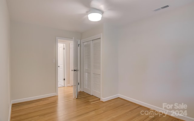 unfurnished bedroom with ceiling fan, a closet, and wood-type flooring