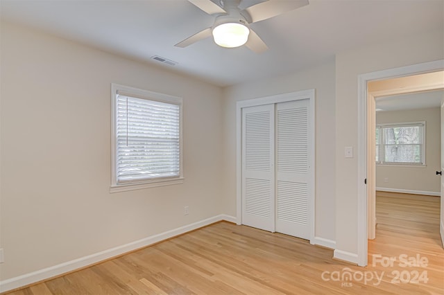 unfurnished bedroom with ceiling fan, a closet, and light wood-type flooring