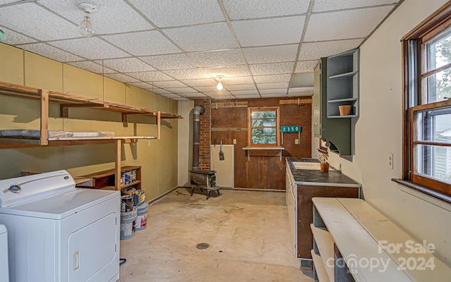 basement with washer / dryer, a wood stove, a drop ceiling, and sink