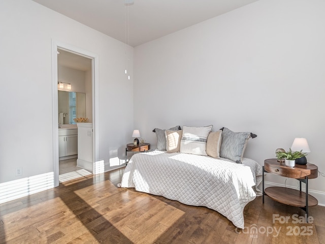 bedroom with ensuite bath and wood-type flooring