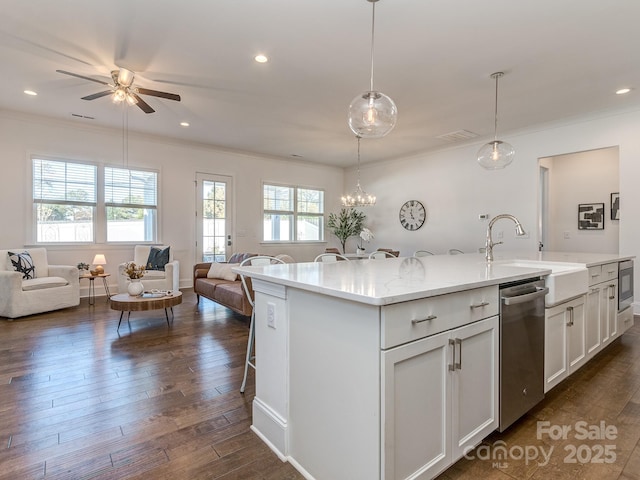 kitchen with ceiling fan, an island with sink, decorative light fixtures, a breakfast bar area, and white cabinets