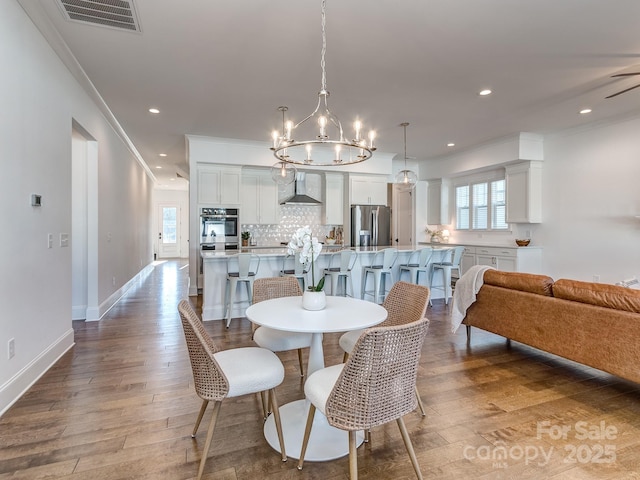 dining area featuring hardwood / wood-style floors, plenty of natural light, ornamental molding, and ceiling fan with notable chandelier