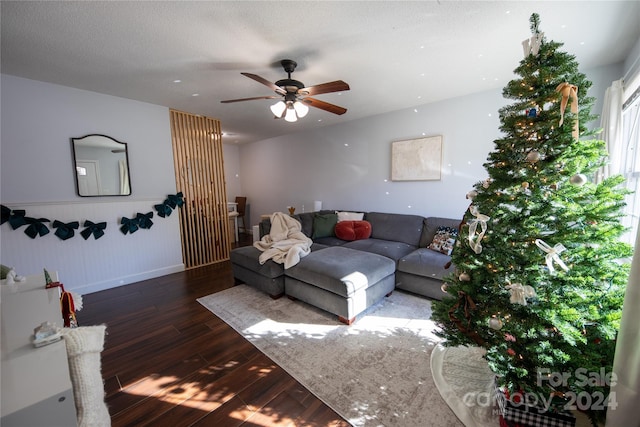 living room with a textured ceiling, ceiling fan, and dark wood-type flooring