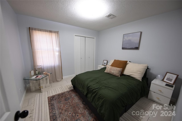 bedroom featuring light tile patterned floors, a textured ceiling, and a closet