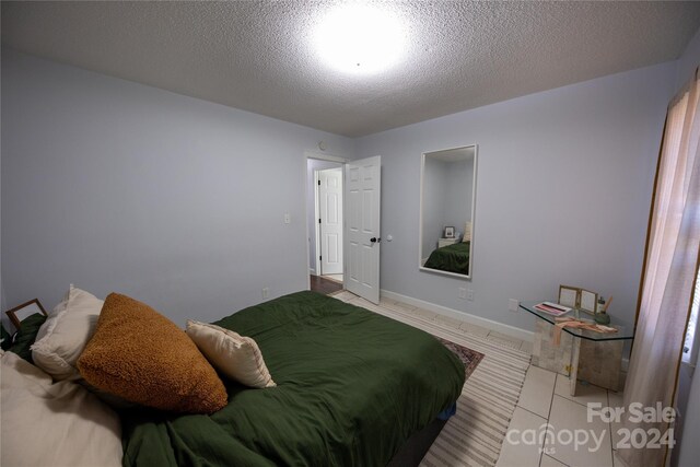 tiled bedroom featuring a textured ceiling