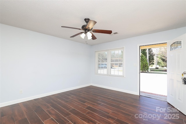 empty room with baseboards, visible vents, ceiling fan, dark wood-type flooring, and a textured ceiling