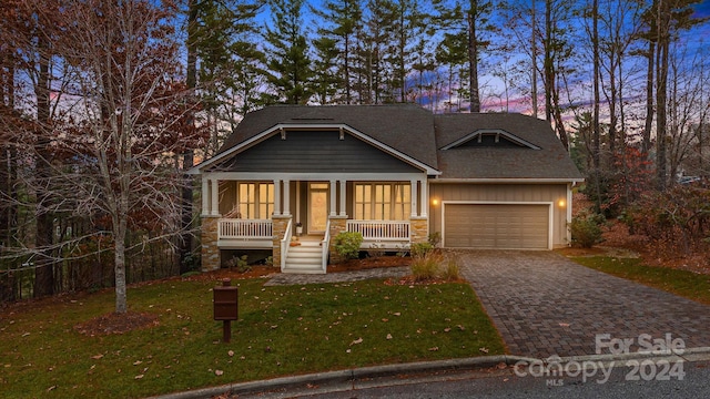 craftsman inspired home with covered porch, a garage, and a lawn