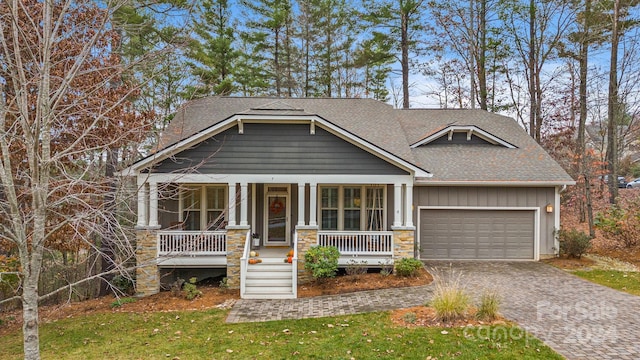 craftsman-style house featuring a front lawn, a porch, and a garage