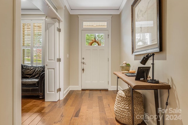 foyer entrance with light hardwood / wood-style floors, a wealth of natural light, and crown molding