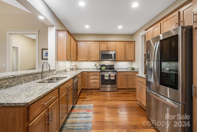 kitchen featuring sink, light hardwood / wood-style flooring, light stone counters, kitchen peninsula, and stainless steel appliances