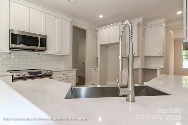 kitchen with white cabinets, a sink, tasteful backsplash, recessed lighting, and appliances with stainless steel finishes