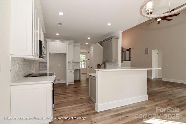 kitchen featuring stainless steel microwave, tasteful backsplash, electric range, visible vents, and a ceiling fan