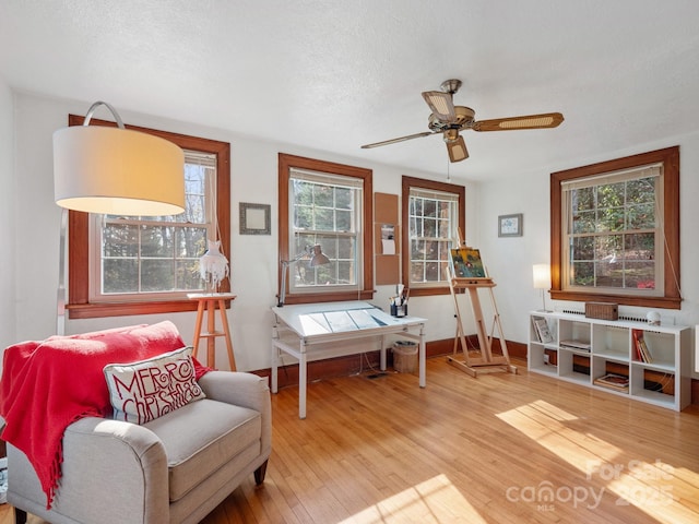 sitting room featuring ceiling fan, light hardwood / wood-style floors, and a textured ceiling