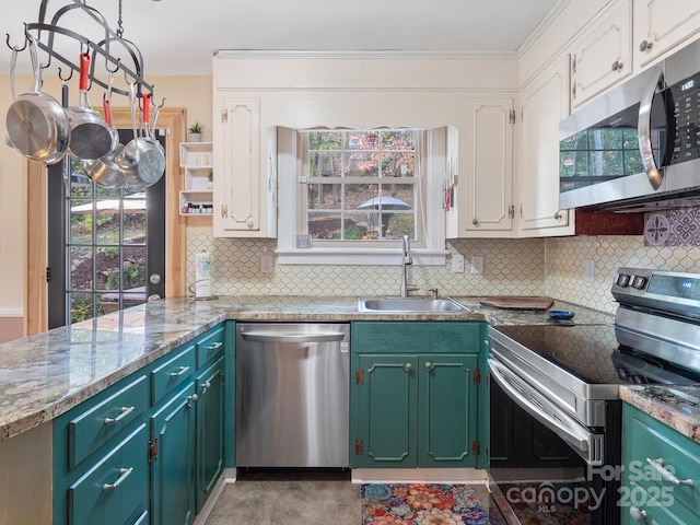 kitchen with appliances with stainless steel finishes, tasteful backsplash, white cabinetry, sink, and light stone countertops