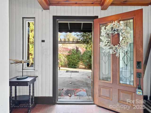 doorway featuring wooden walls and beam ceiling