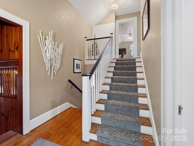 staircase featuring wood-type flooring and lofted ceiling