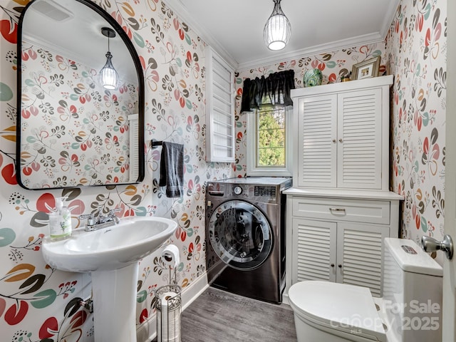 bathroom with crown molding, toilet, washer / dryer, and hardwood / wood-style flooring