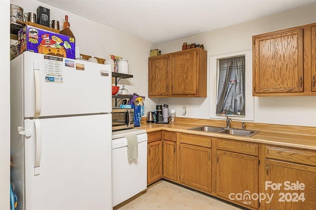 kitchen featuring a textured ceiling, white appliances, and sink