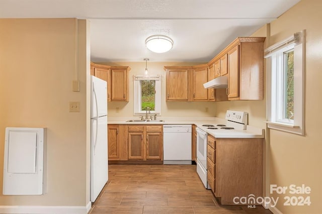 kitchen featuring light wood-type flooring, white appliances, sink, and hanging light fixtures