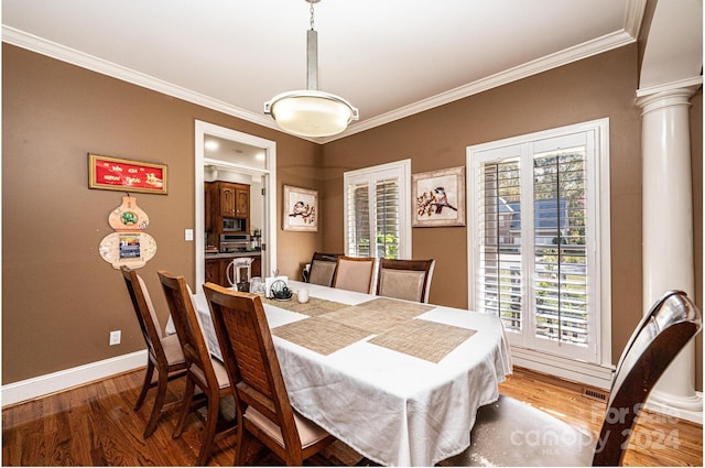 dining space with decorative columns, crown molding, and wood-type flooring