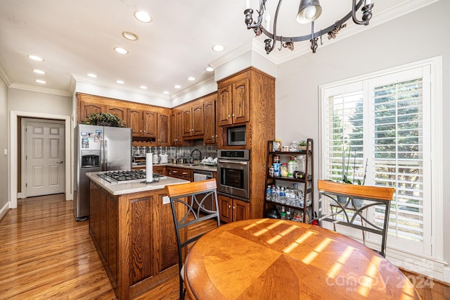 kitchen featuring decorative backsplash, light wood-type flooring, stainless steel appliances, crown molding, and a center island