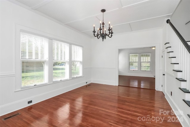 spare room with crown molding, dark wood-type flooring, and a notable chandelier