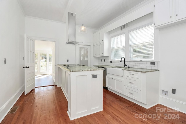 kitchen with hardwood / wood-style flooring, decorative light fixtures, white cabinetry, and wall chimney range hood