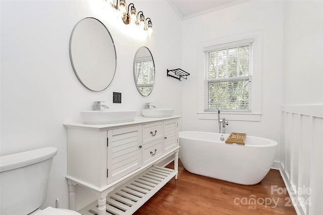 bathroom with hardwood / wood-style floors, vanity, toilet, ornamental molding, and a tub