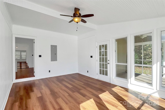 spare room with electric panel, ceiling fan, vaulted ceiling with beams, and hardwood / wood-style flooring