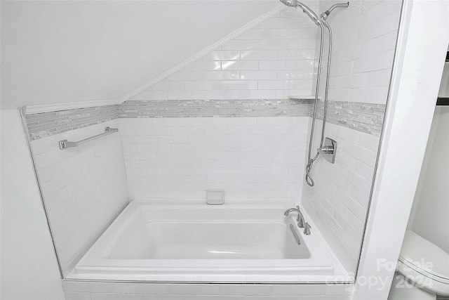 bathroom featuring toilet and tiled shower / bath