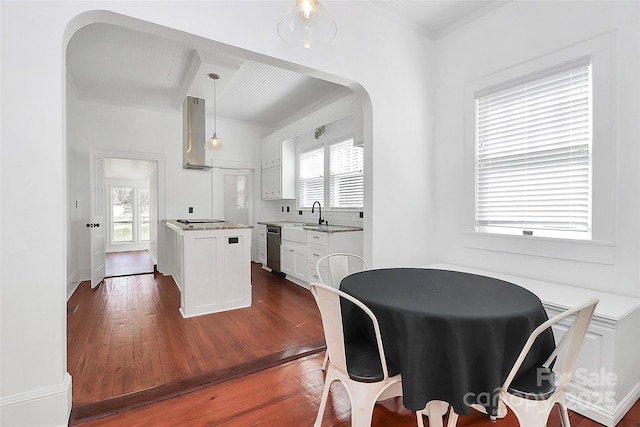 dining room with arched walkways and dark wood-style floors