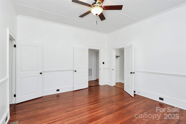 unfurnished bedroom with visible vents, ornamental molding, baseboards, and wood finished floors