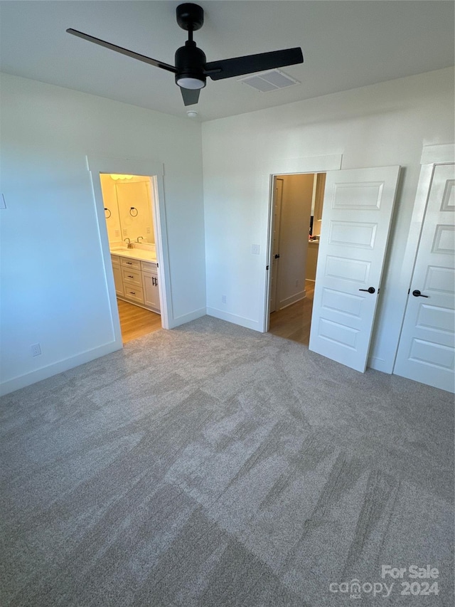 unfurnished bedroom featuring ensuite bathroom, ceiling fan, and light colored carpet