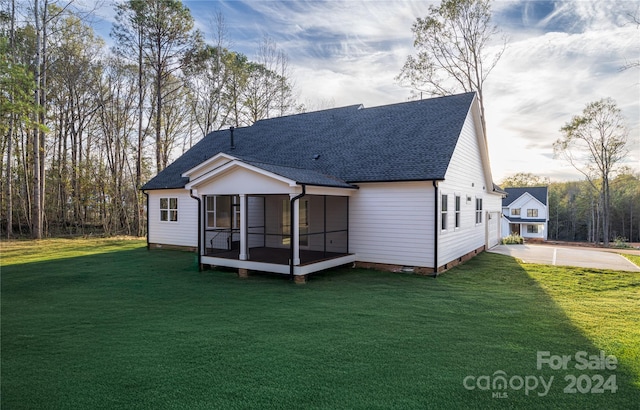 back of property with a sunroom and a lawn