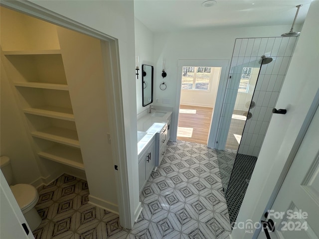 bathroom with a tile shower, tile patterned floors, vanity, and toilet