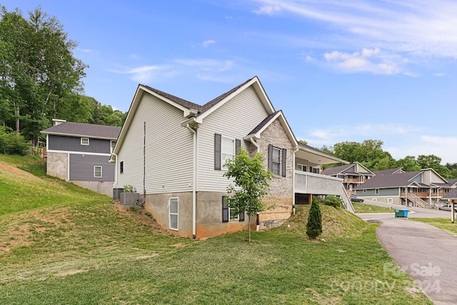 view of property exterior with a yard and central air condition unit