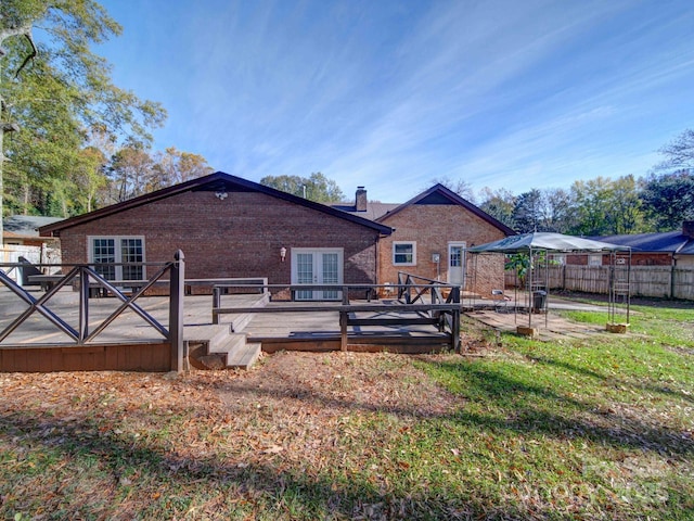 rear view of house with a wooden deck, a lawn, and french doors