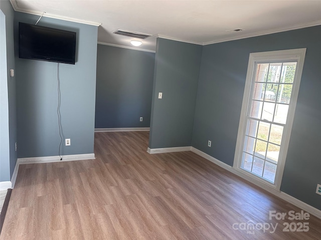 empty room with ornamental molding and light hardwood / wood-style flooring