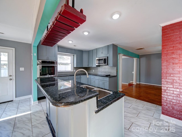 kitchen with sink, dark stone counters, a kitchen island, stainless steel appliances, and decorative backsplash