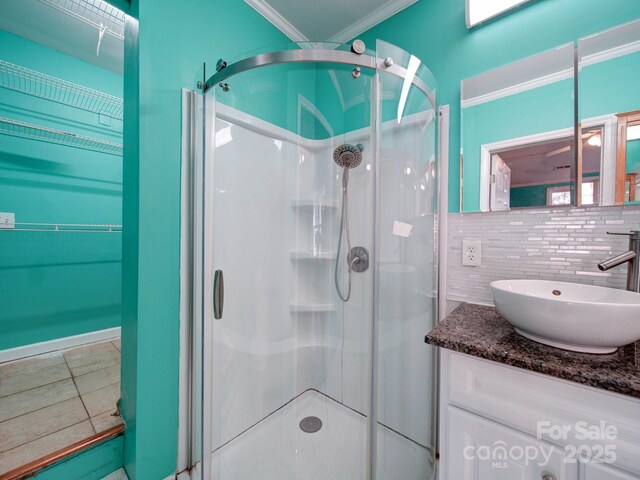 bathroom with crown molding, vanity, an enclosed shower, and backsplash