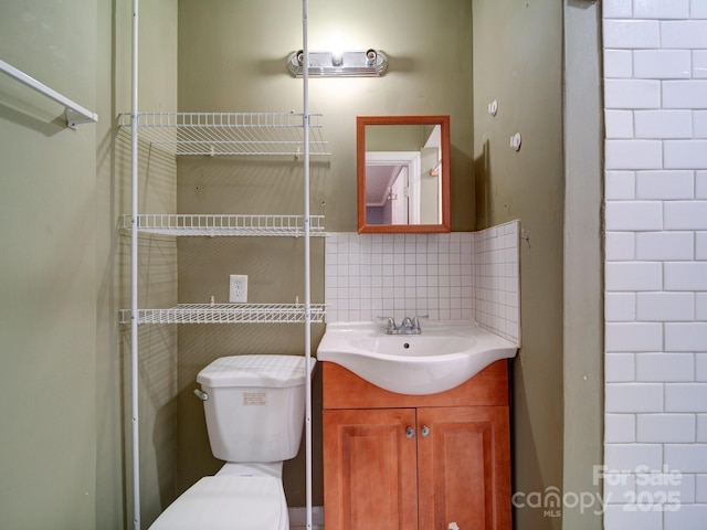 bathroom featuring vanity, toilet, and decorative backsplash