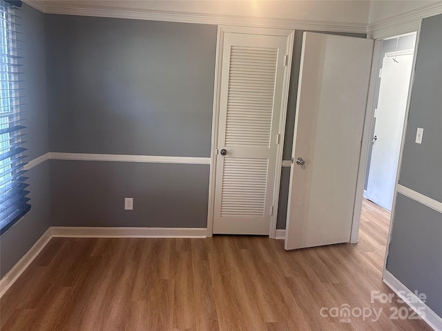 unfurnished bedroom with hardwood / wood-style flooring, ornamental molding, and a closet