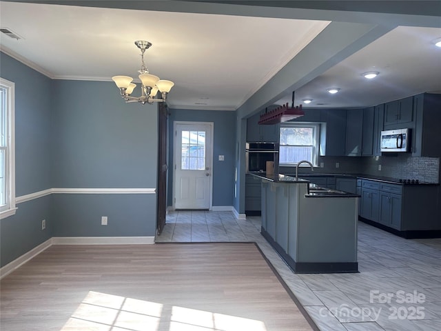 kitchen with pendant lighting, sink, crown molding, and stainless steel appliances