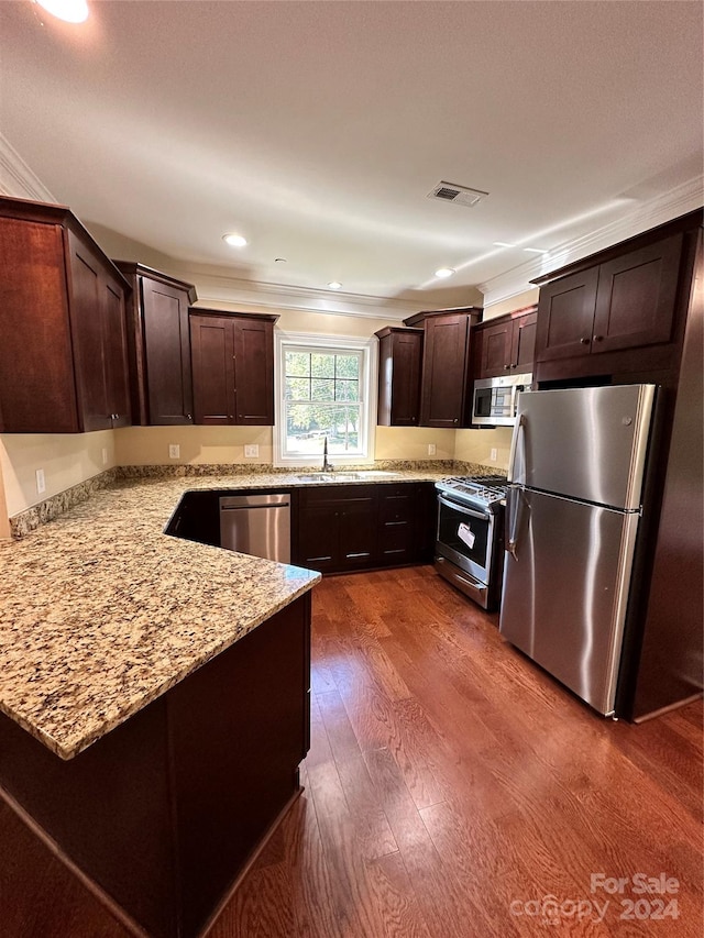 kitchen featuring light stone countertops, dark hardwood / wood-style flooring, dark brown cabinetry, stainless steel appliances, and crown molding