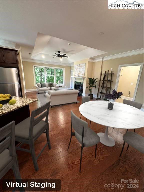 dining room with a raised ceiling, ceiling fan, dark wood-type flooring, and ornamental molding