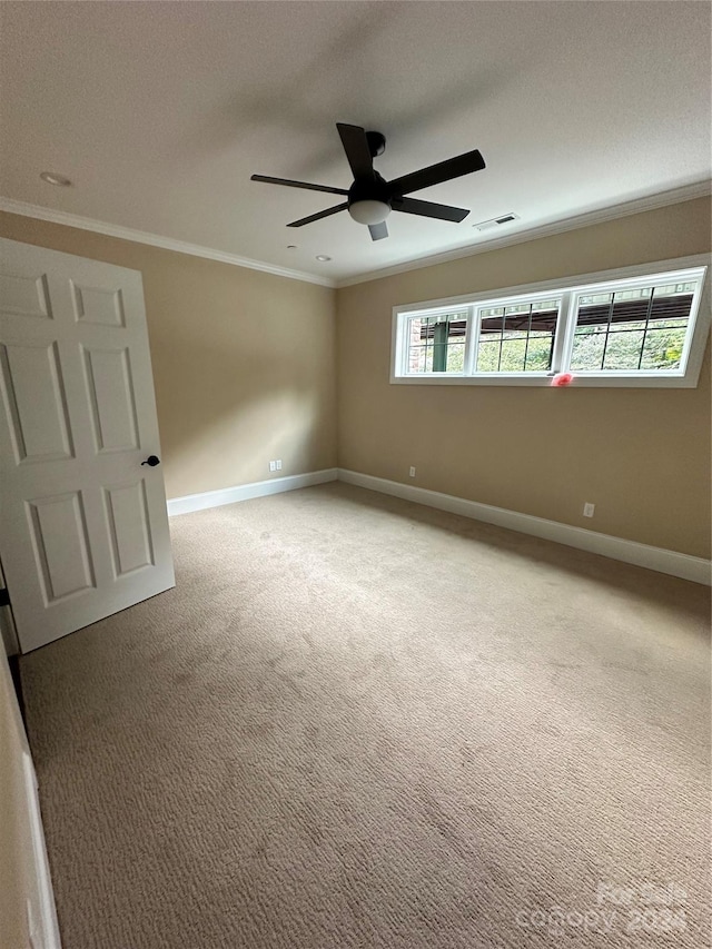 empty room with carpet floors, a wealth of natural light, ornamental molding, and ceiling fan