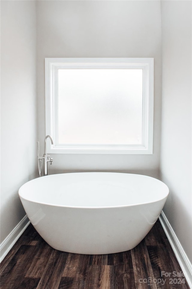 bathroom featuring a bath, hardwood / wood-style flooring, and plenty of natural light